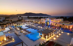 A resort with multiple swimming pools, outdoor seating areas, and a view of the sea at sunset. - Anemos Luxury Grand Resort (Apokoronas)
