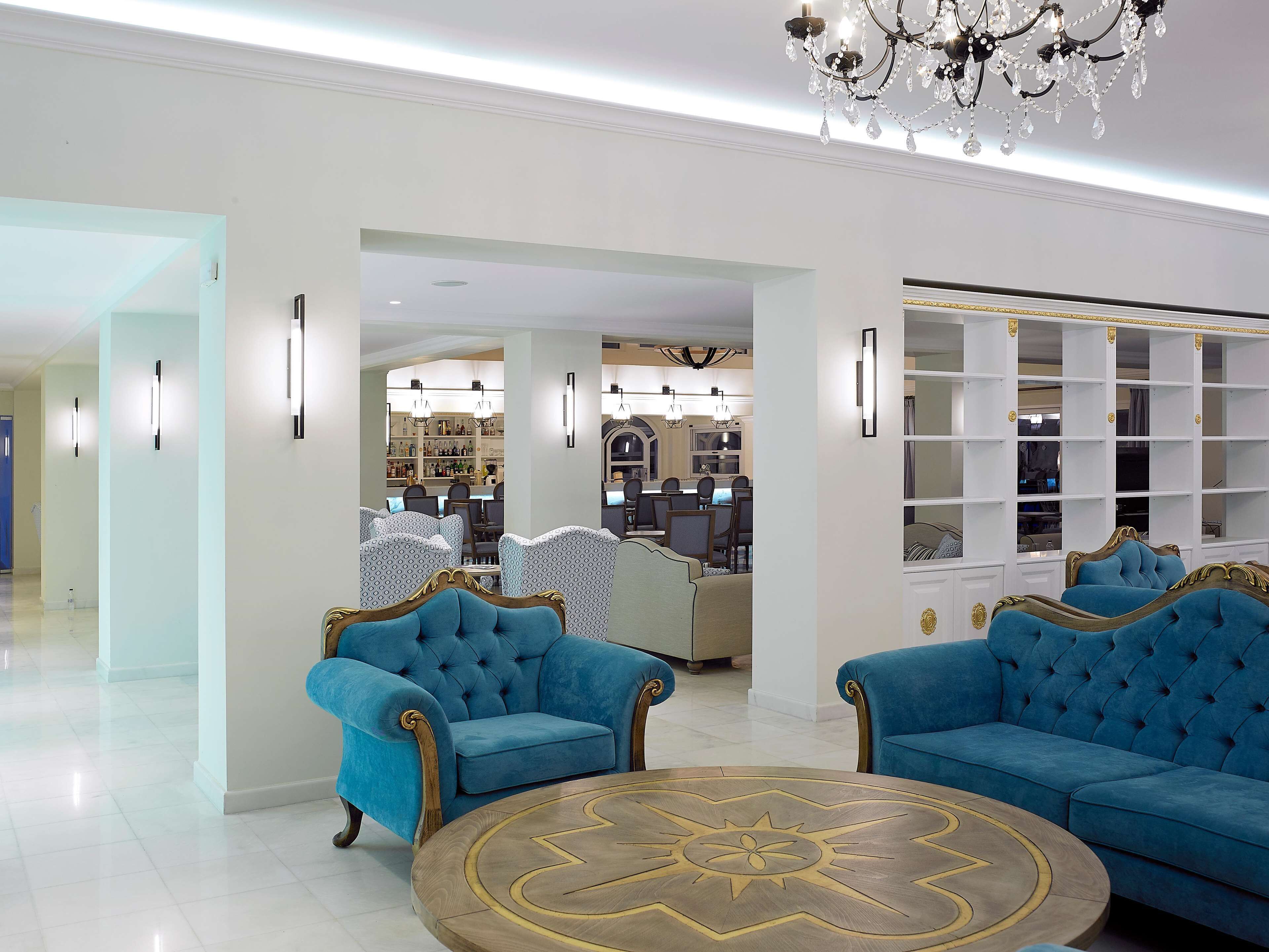 Amplia sala de estar con candelabro, sofás tapizados en azul y una mesa de centro redonda con diseño decorativo.