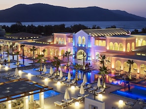 Ein Resort mit großem Pool, Liegestühlen und Meerblick.