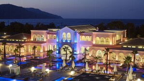 A resort with multiple swimming pools, outdoor seating areas, and a large building with arched windows. - Anemos Luxury Grand Resort (Apokoronas)