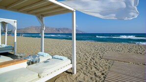 A beachside lounge with a wooden deck and a covered seating area. - Anemos Luxury Grand Resort (Apokoronas)
