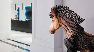 Un intérieur moderne agrémenté d’une sculpture équestre en bois et d’un espace d’accueil éclairé de lumière bleue.
