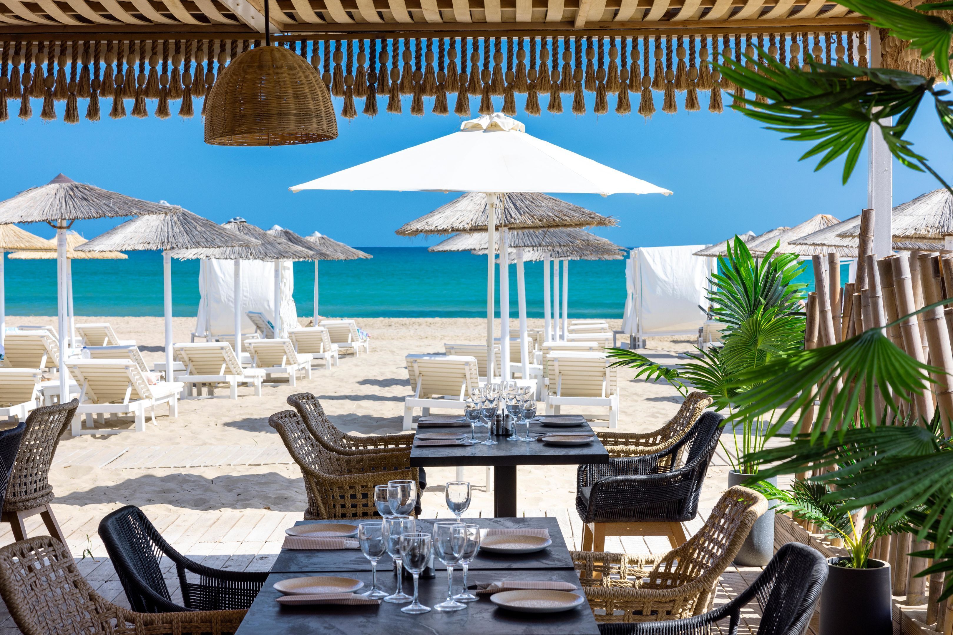 Ein Restaurant am Strand mit Außenbereich, Sonnenschirmen und Blick auf das Meer.