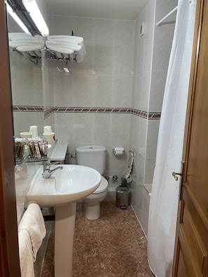 Un baño con lavamanos, inodoro y cortina de ducha.