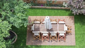 A wooden deck with a table and chairs, surrounded by a garden with various plants and a wooden fence. - Flower Pot Complex (Preveza)