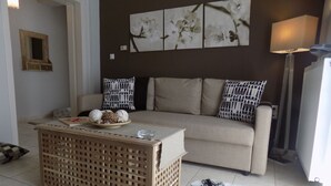 A living room with a beige sofa, patterned pillows, a wooden coffee table, and a fur rug. - Flower Pot Complex (Preveza)