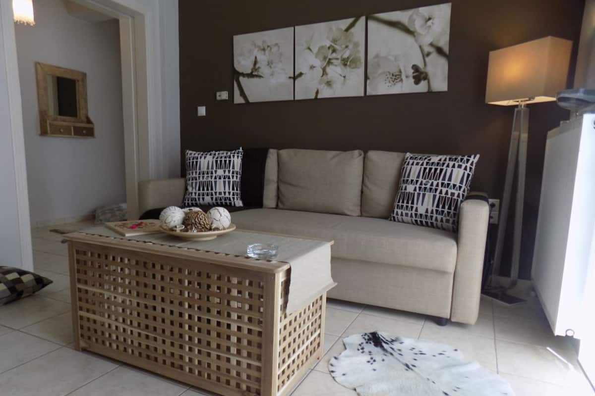 Una sala de estar con un sofá color beige, almohadones estampados, una mesa de centro de madera y una alfombra de piel.