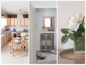 A modern kitchen with wooden cabinets, a dining area with a table set for two, and a decorative mirror above a cabinet.