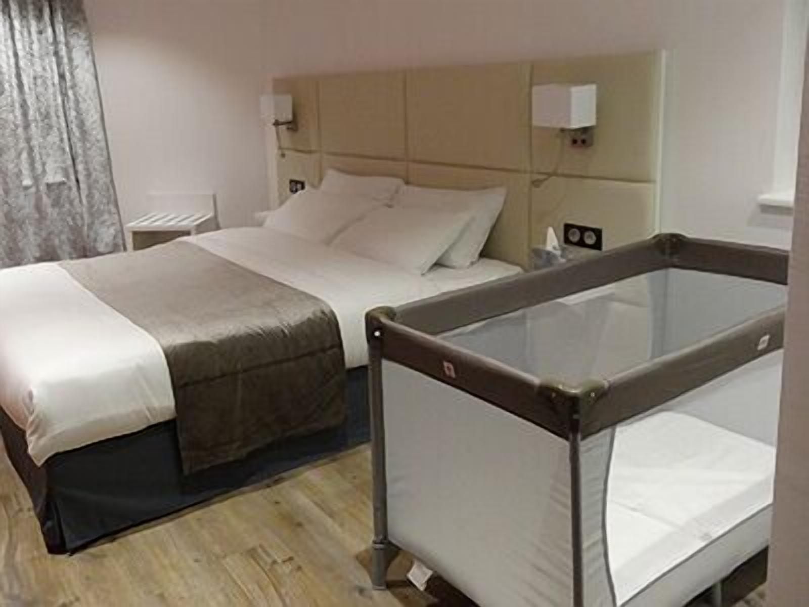 Una habitación de hotel con cama, lámparas de noche, un panel de vidrio y suelo de madera.