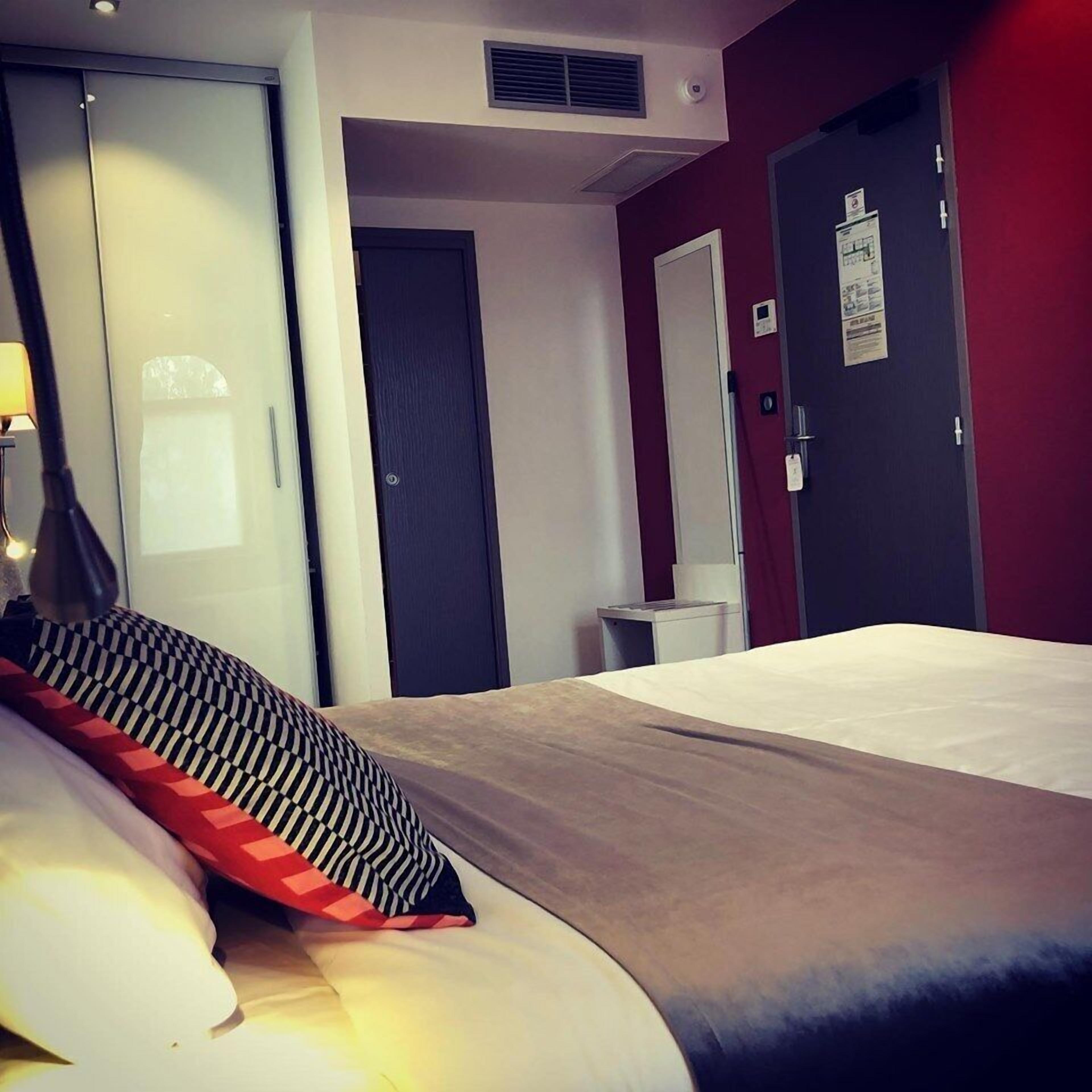 A hotel room with a bed, a desk, and a wardrobe.