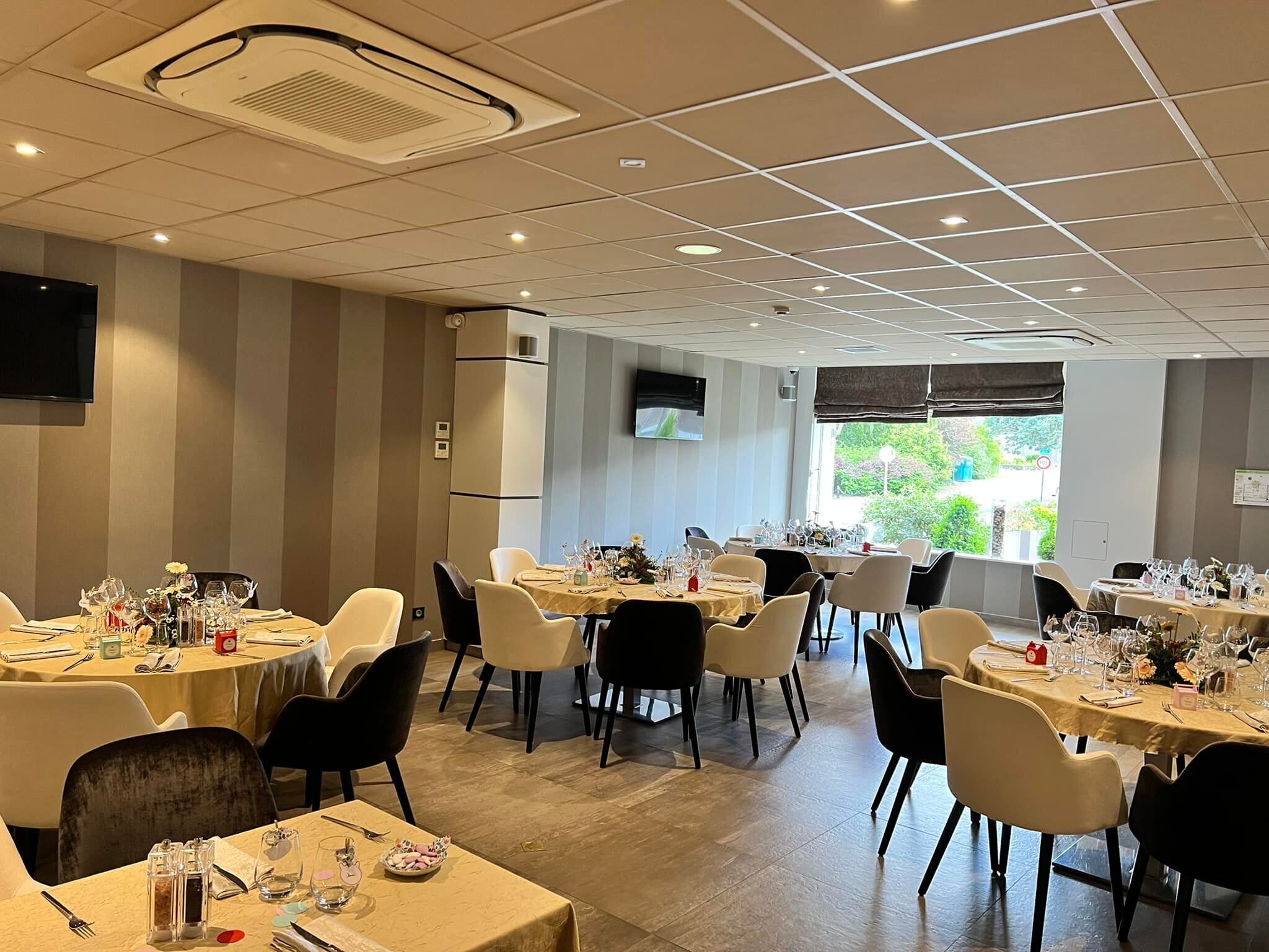 Uma sala de jantar com várias mesas preparadas para refeições, equipada com cadeiras, toalhas de mesa e utensílios.