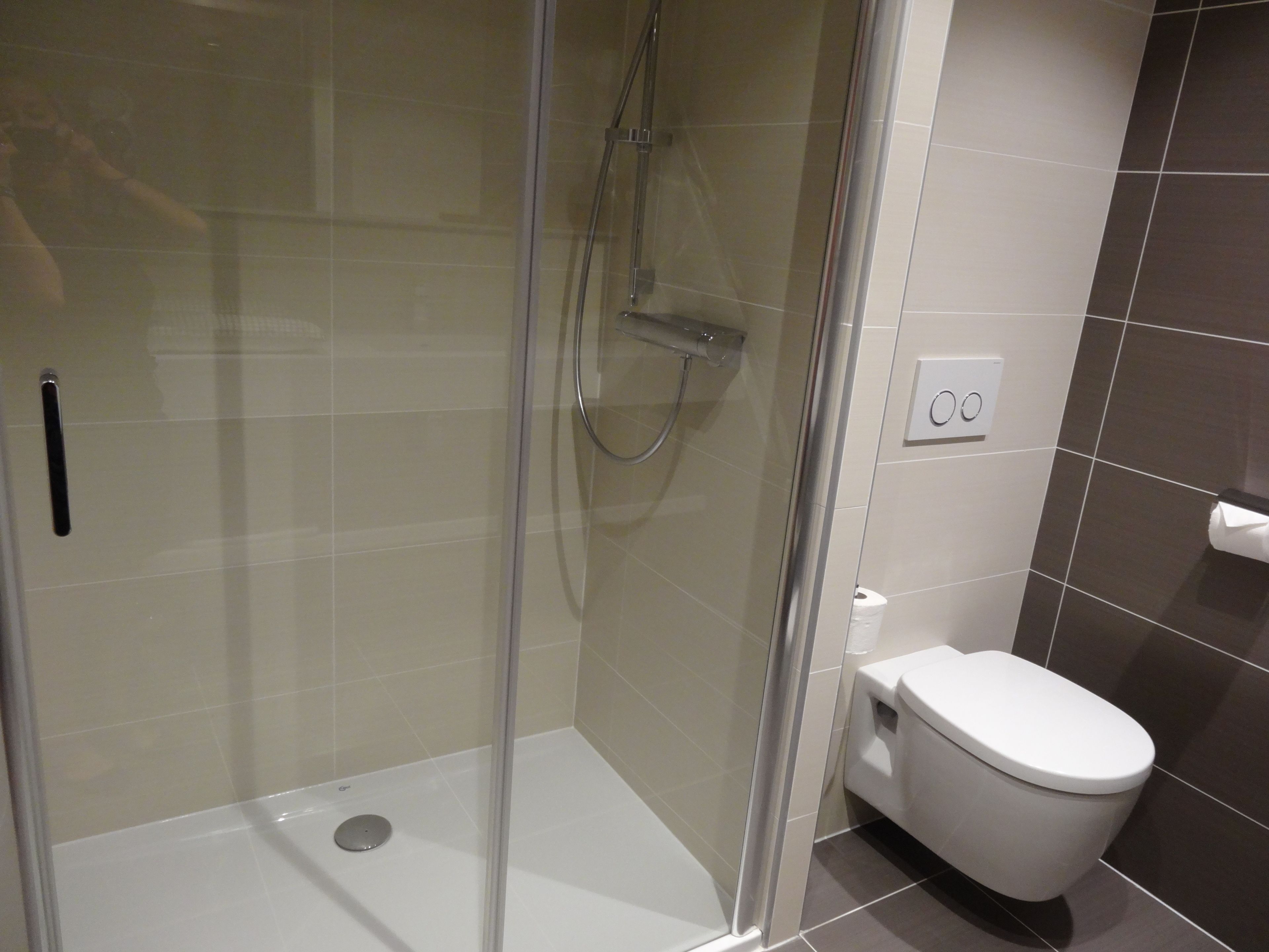 Ein modernes Badezimmer mit einer gläsernen Duschkabine, einer Toilette und einem an der Wand befestigten Handtuchhalter.
