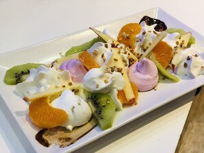 Un plato de postre con varias frutas y crema batida.