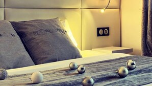 Un dormitorio moderno con un tablero de cabecera capitonado, lámparas de noche y objetos esféricos decorativos sobre la cama.