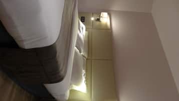 Een hotelkamer met een bed, nachtkastje, lamp en een wandlamp.