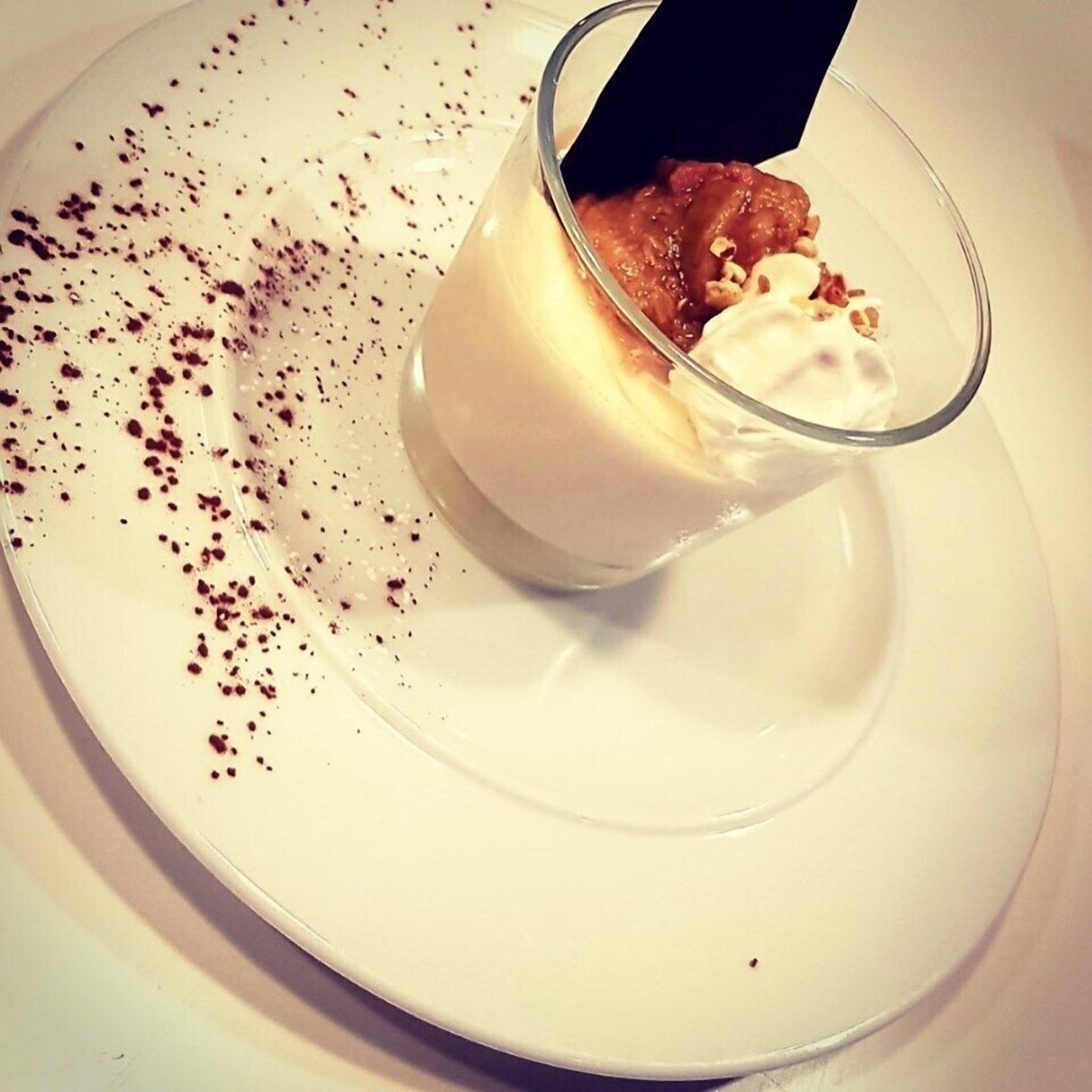 Een dessert met slagroom en een gekarameliseerde topping, geserveerd op een wit bord.
