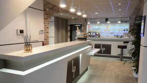 Un área de recepción de diseño moderno, con un mostrador de recepción, un cartel que dice 'Reception' y una zona de bar con estantes llenos de botellas.