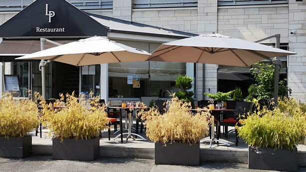 Un área de estar al aire libre con mesas y sombrillas en un restaurante.
