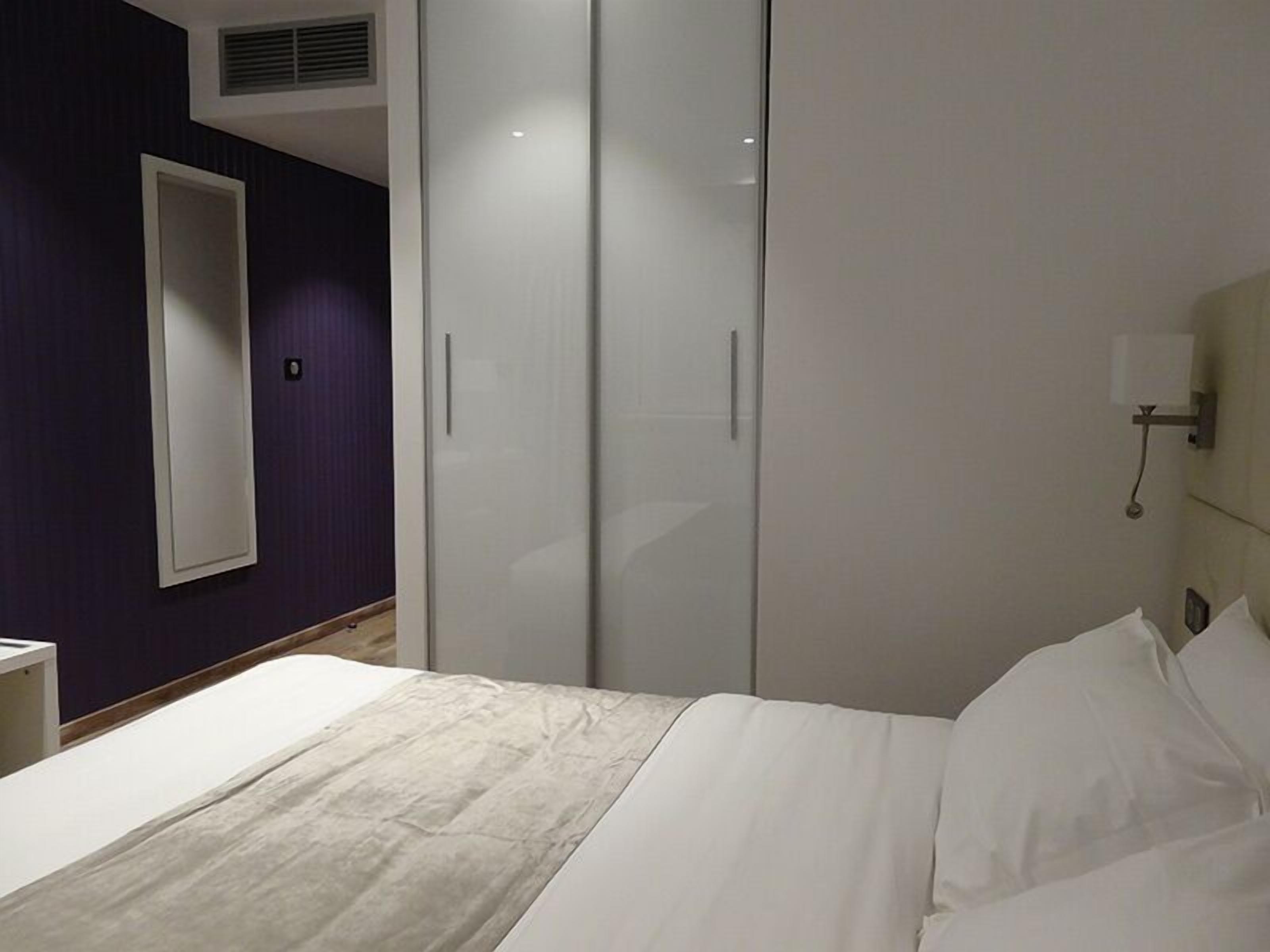 A bedroom with a bed, a wardrobe, and a nightstand.