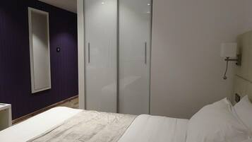 A bedroom with a bed, a wardrobe, and a nightstand.