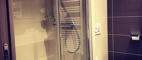 Un baño moderno con cabina de ducha de vidrio, inodoro blanco y toallero.