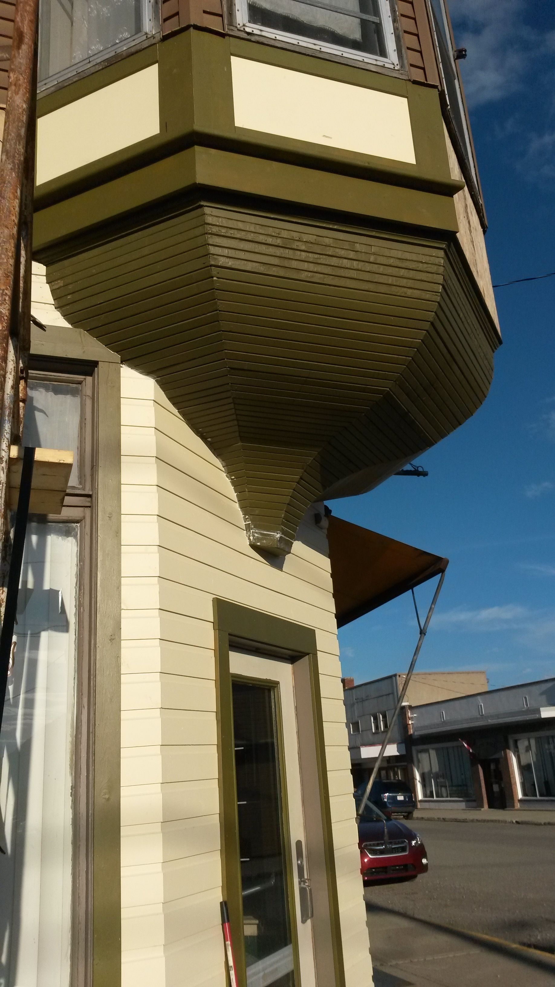 A corner of a building with a green awning and a window.