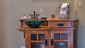 A wooden vanity with a green marble basin, two wall-mounted lights, a mirror, and a towel rack. - Country Encounters (Coleman)
