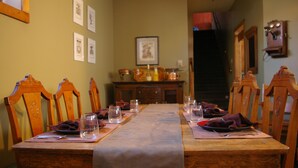 A dining table set with plates, glasses, and napkins, flanked by wooden chairs. - Country Encounters (Coleman)