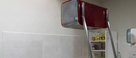 A kitchen with a red toaster, a wooden cutting board, and a pink utensil holder.