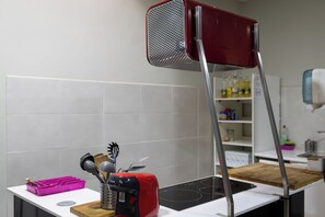 Een keuken met een rode broodrooster, een houten snijplank en een roze bestekhouder.