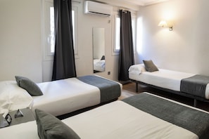 A hotel room with two single beds, a mirror, a wall-mounted lamp, and an air conditioning unit. - Hotel Alda Centro Palencia (Palencia)