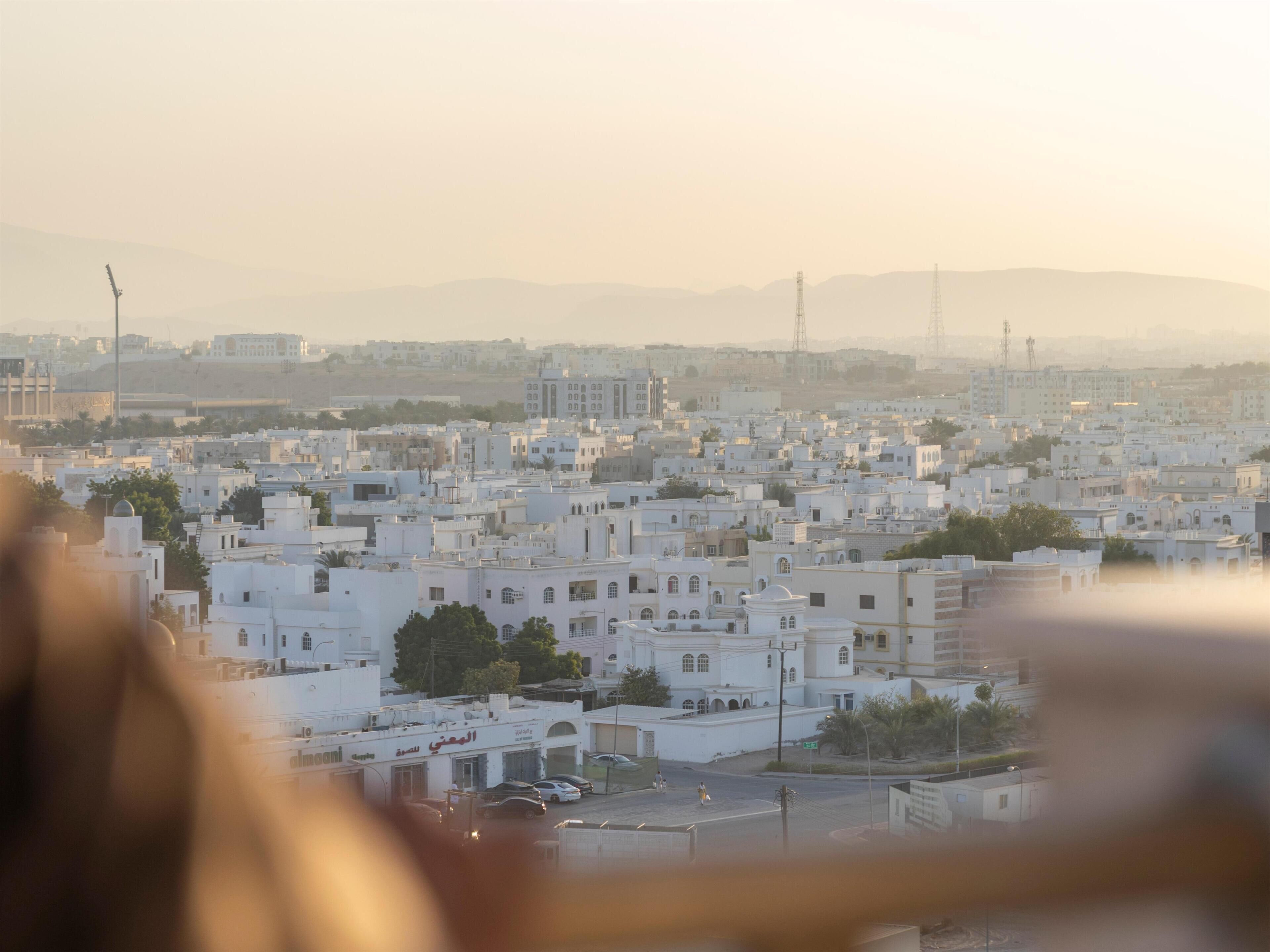 Une vue urbaine avec des bâtiments blancs, une mosquée et une rue où circulent des voitures.