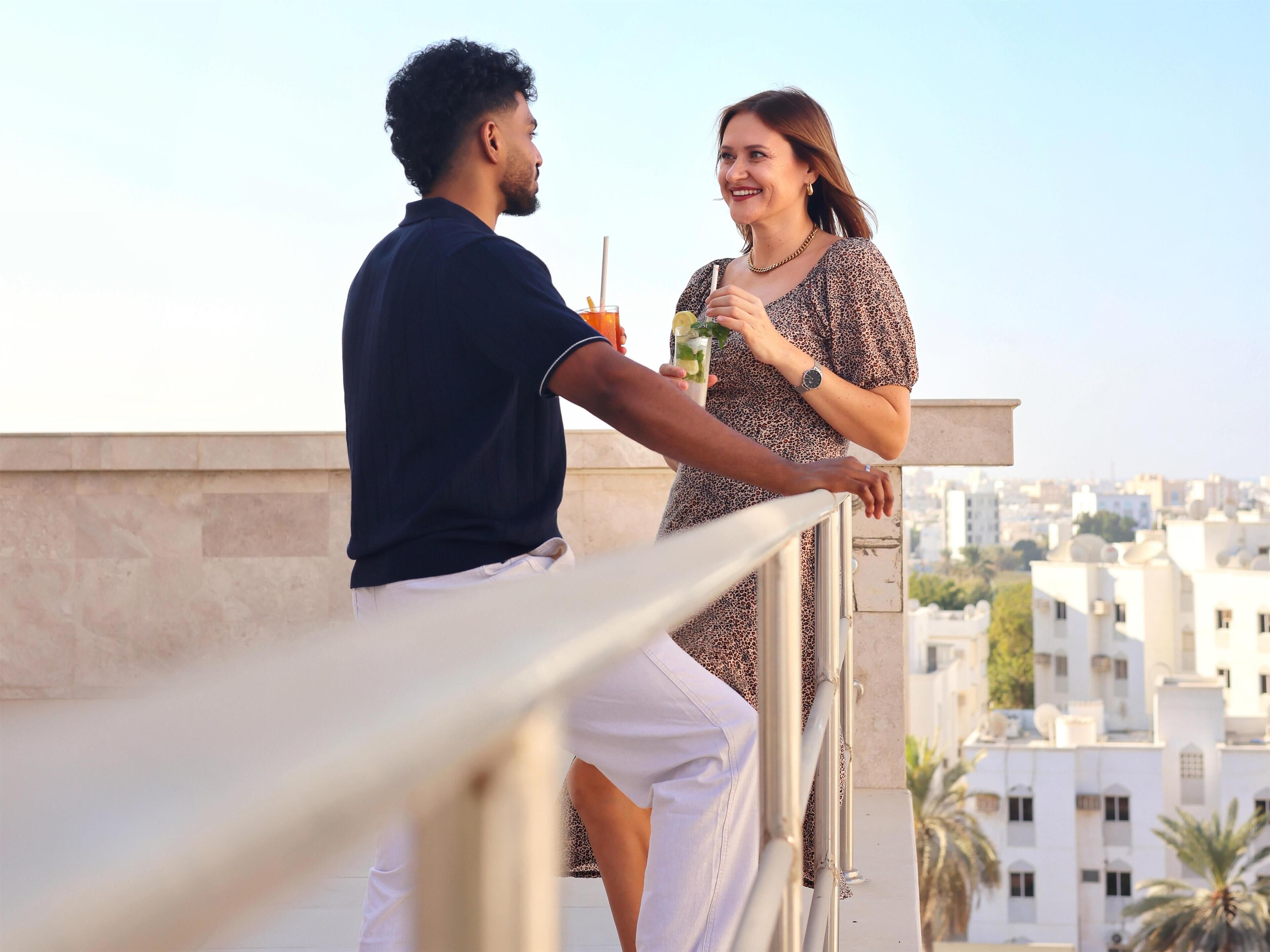 Una pareja en un balcón con vistas a una ciudad.