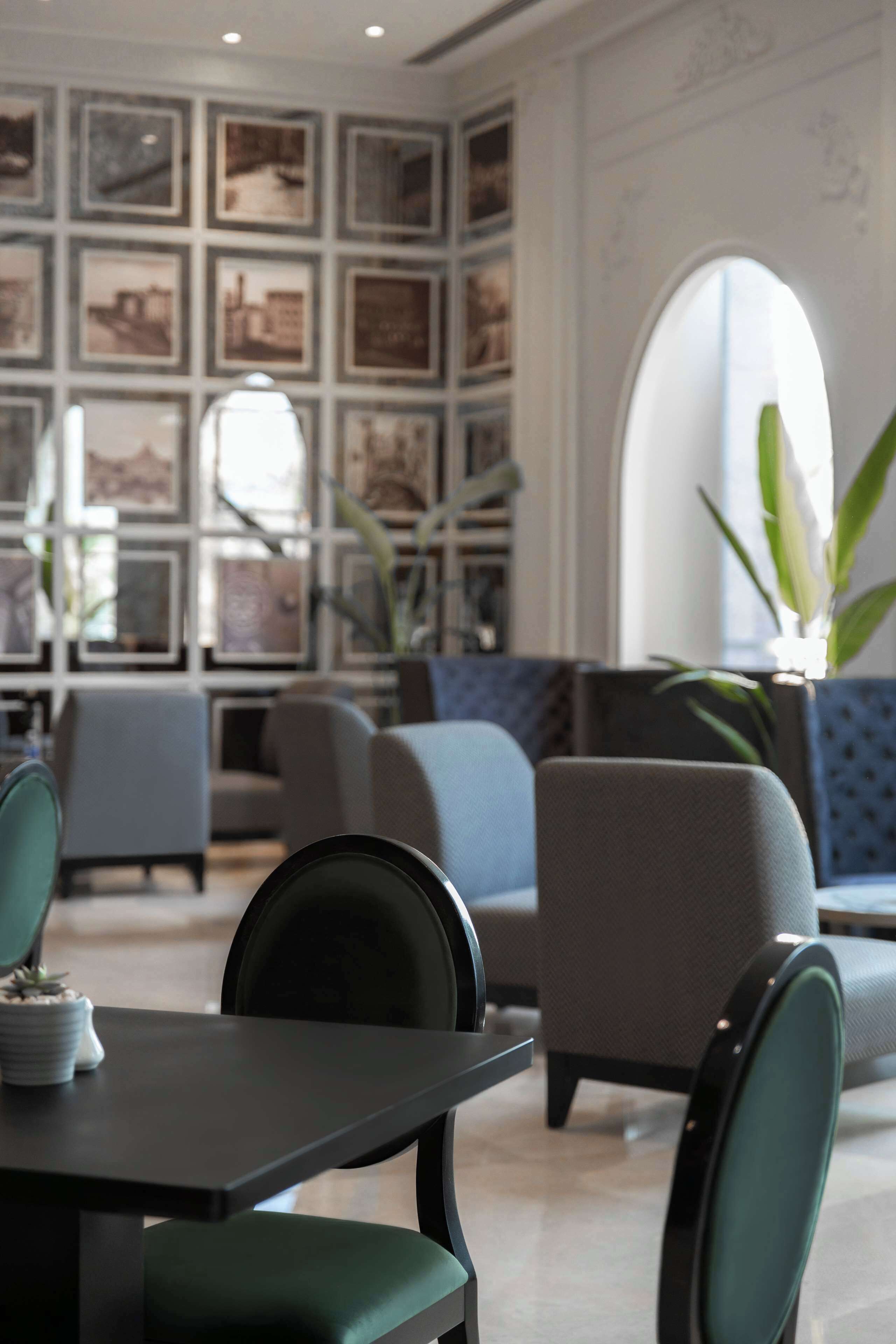 Un espace de détente moderne, avec une table et des chaises aux tons foncés, un canapé bleu et un mur décoré de tableaux encadrés.