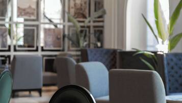 Un espace de détente moderne, avec une table et des chaises aux tons foncés, un canapé bleu et un mur décoré de tableaux encadrés.