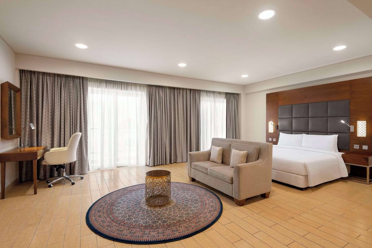 Une chambre d’hôtel avec un lit, un canapé, un bureau et une chaise.