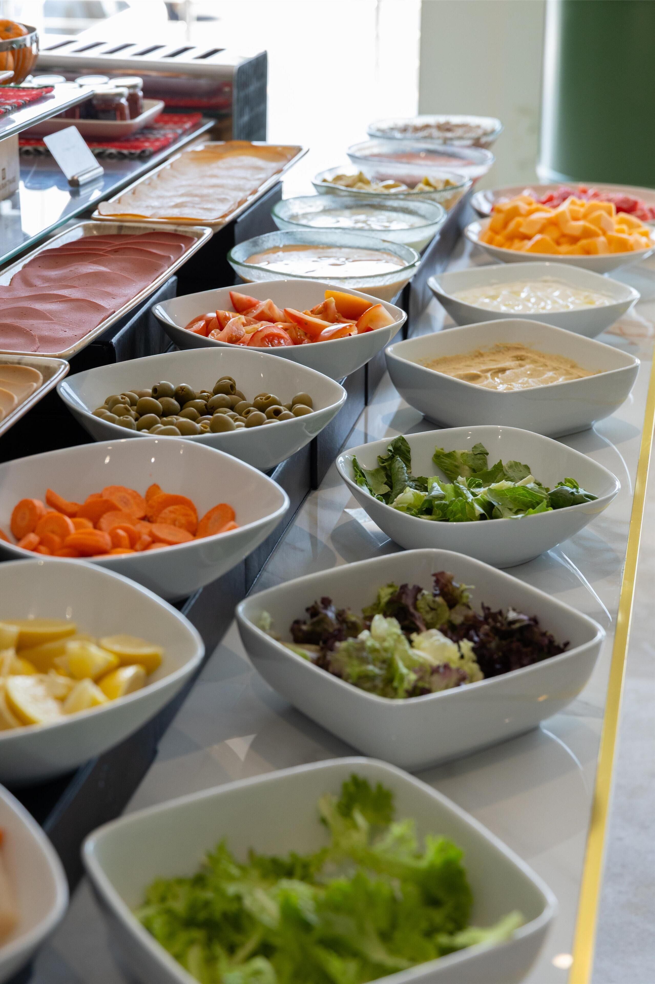Ein reichhaltiges Buffet mit verschiedenen Speisen, darunter Salate, Früchte und Dips.