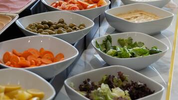Ein reichhaltiges Buffet mit verschiedenen Speisen, darunter Salate, Früchte und Dips.