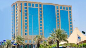Un hotel alto con fachada azul y un cartel que dice "MOVEPICK".