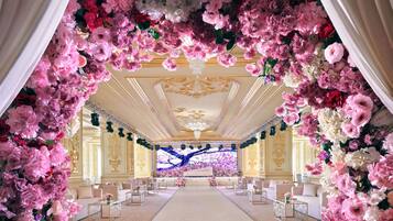 Ein prachtvoller Saal mit einem Blumengestall, stilvoller Sitzgelegenheiten und einer großen Leinwand im Vordergrund.