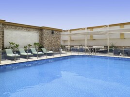 Una piscina al aire libre, sombrillas, sillones reclinables de piscina