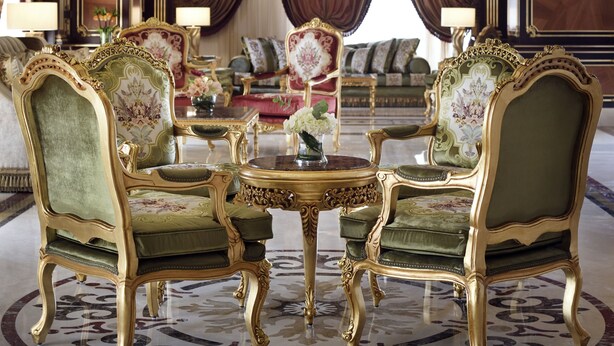 Una habitación opulenta con muebles ornamentados, un candelabro y un piano de cola.