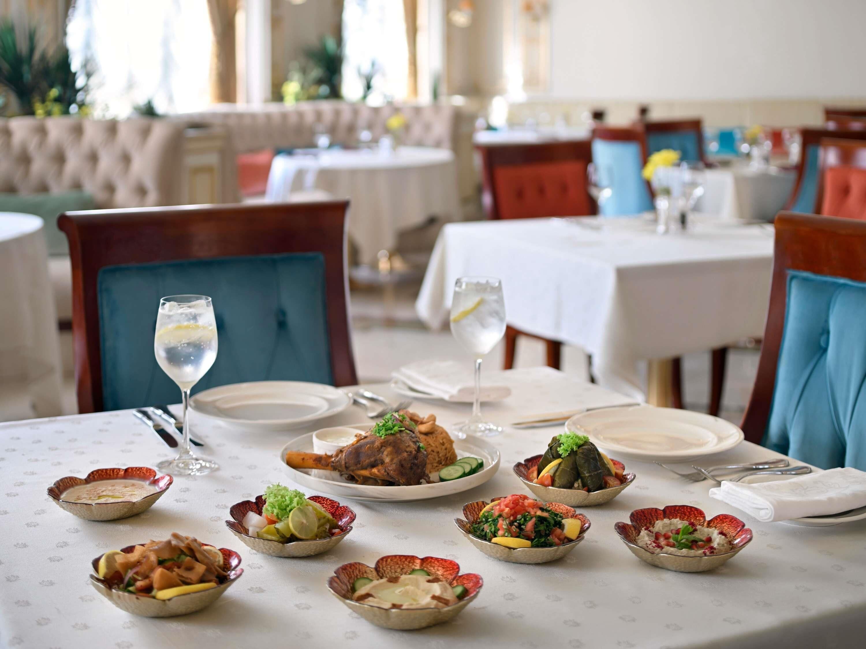 A dining area with tables set for a meal, including plates of food and glasses of water.