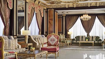 Ein luxuriöses Zimmer mit aufwendigen Möbeln, einem Chandelier und großen, mit Vorhängen versehenen Fenstern.