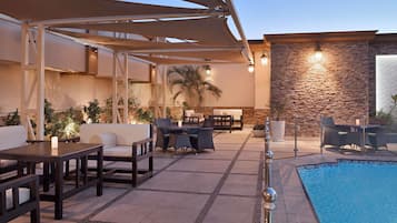 Un área de piscina al aire libre con sillones de descanso y una pared de piedra.