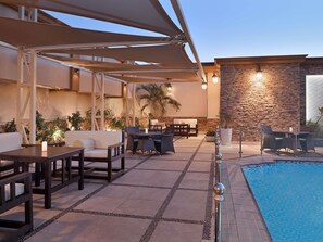 An outdoor pool area with lounge seating and a stone wall.