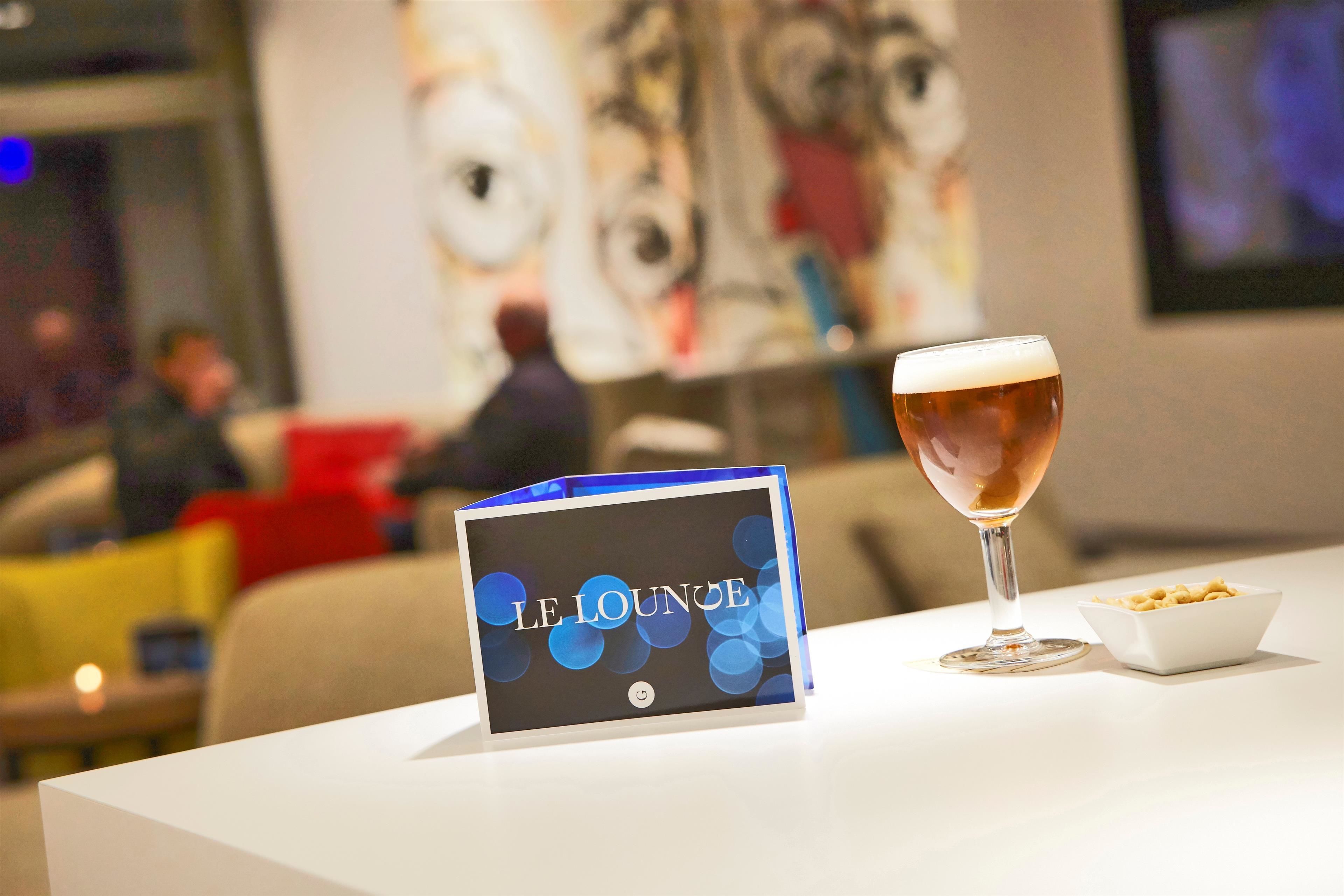 Una mesa con una jarra de cerveza, un plato de pasta y un menú que dice "LE LOUNGE".