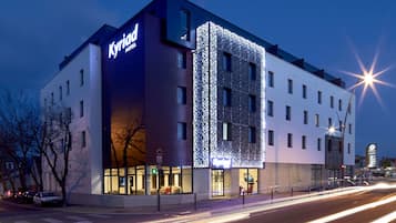 A modern hotel with a prominent sign, multiple floors, and a well-lit facade.