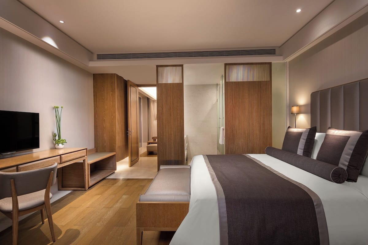 Une chambre d’hôtel moderne, dotée d’un grand lit, d’un bureau et d’une télévision.