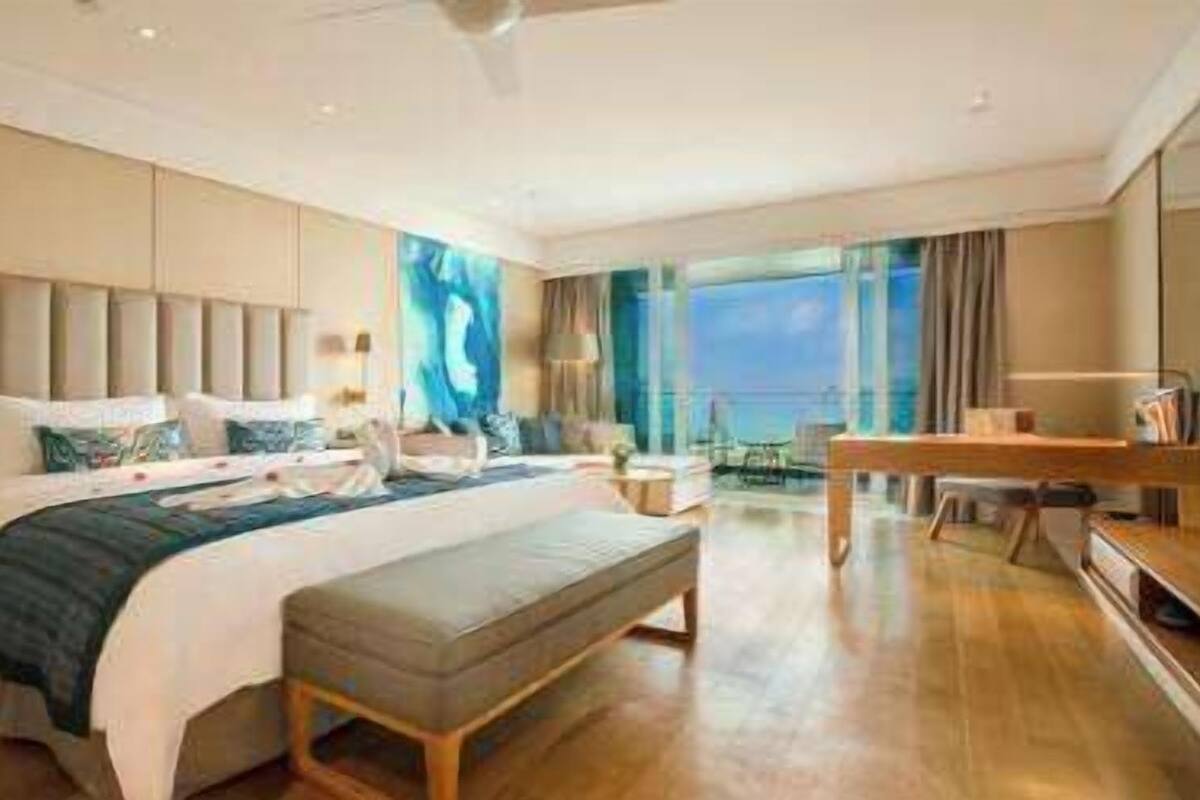 Une chambre d’hôtel moderne avec un grand lit, un bureau et une vue sur la mer.